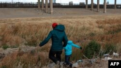 Migrant iz Gvatamale sa sinom prelazi reku Rio Grande, prirodnu granicu između El Pasa u državi Teksas i Kjudad Huareza, u državi Čivava u Meksiku, u potrazi za političkim azilom, 26. januara 2021. (Photo by HERIKA MARTINEZ / AFP)
