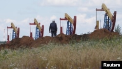 A worker stands in front of pump jacks at the Ashalchinskoye oil field owned by Russia's oil producer Tatneft near Almetyevsk, in the Republic of Tatarstan, Russia, July 27, 2017