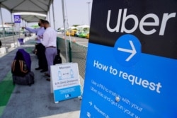 FILE - Travelers request an Uber ride at Los Angeles International Airport's LAX-it pick up terminal, Aug. 20, 2020.