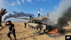 Palestinci slave pored uništenog izraelskog tenka u pojasu Gaze (Foto: AP/Hassan Eslaiah)