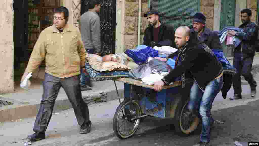 People wheel a sick man on a makeshift stretcher at the Karaj al-Hajez crossing in Aleppo, Feb. 9, 2014.