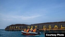 Aktivis Greenpeace menulis "Coral not Coal" di lambung tongkang batubara di Karimunjawa. (Foto: Greenpeace Indonesia).