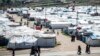 FILE - Women and children walk at Roj camp, where relatives of people suspected of belonging to the Islamic State group are held, in the countryside near al-Malikiyah in Syria's northeastern Hasakah province, March 28, 2021.