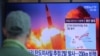 Arhiva - Čovek posmatra TV ekran na kom je prikazana arhivska fotografija lansianja rakete u sklopu emisije vesti, na železničkoj stanici u Seulu, Južna Koreja, 29. marta 2020.