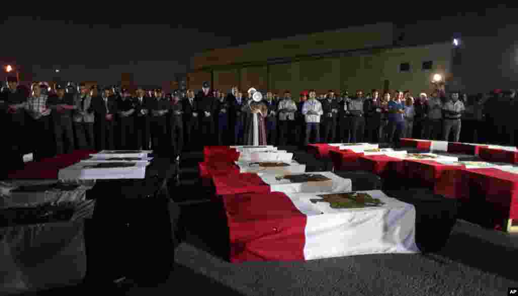 Security officers attend a funeral prayer over coffins covered with national flags of bodies of police who were killed near the border town of Rafah, North Sinai, at Almaza military airport in Cairo, August 19, 2013.