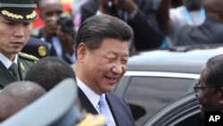 Chinese President Xi Jinping, chats to Zimbabwean President Robert Mugabe, right, upon his arrival in Harare, Zimbabwe, Tuesday, Dec. 1. 2015. Jinping is in Zimbabwe for a two day State visit during which he is set to sign some bilateral agreements aimed at strengthening relationships between the two countries. (AP Photo/Tsvangirayi Mukwazhi)