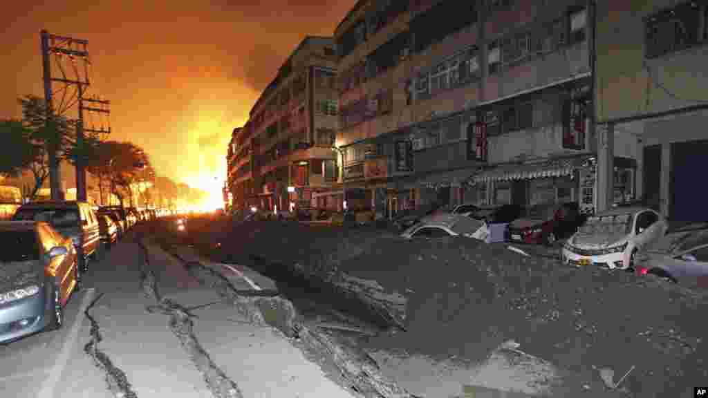 Tossed vehicles line an destroyed street as flames continue to burn from multiple explosions from an underground gas leak in Kaohsiung, Taiwan, Aug. 1, 2014.