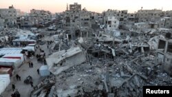 Palestinians walk among the rubble of buildings, amid a ceasefire between Israel and Hamas, in Khan Younis, in the southern Gaza Strip, Feb. 27, 2025.