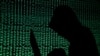 FILE - A hooded man holds a laptop computer as cyber code is projected on him in this picture taken on May 13, 2017. 