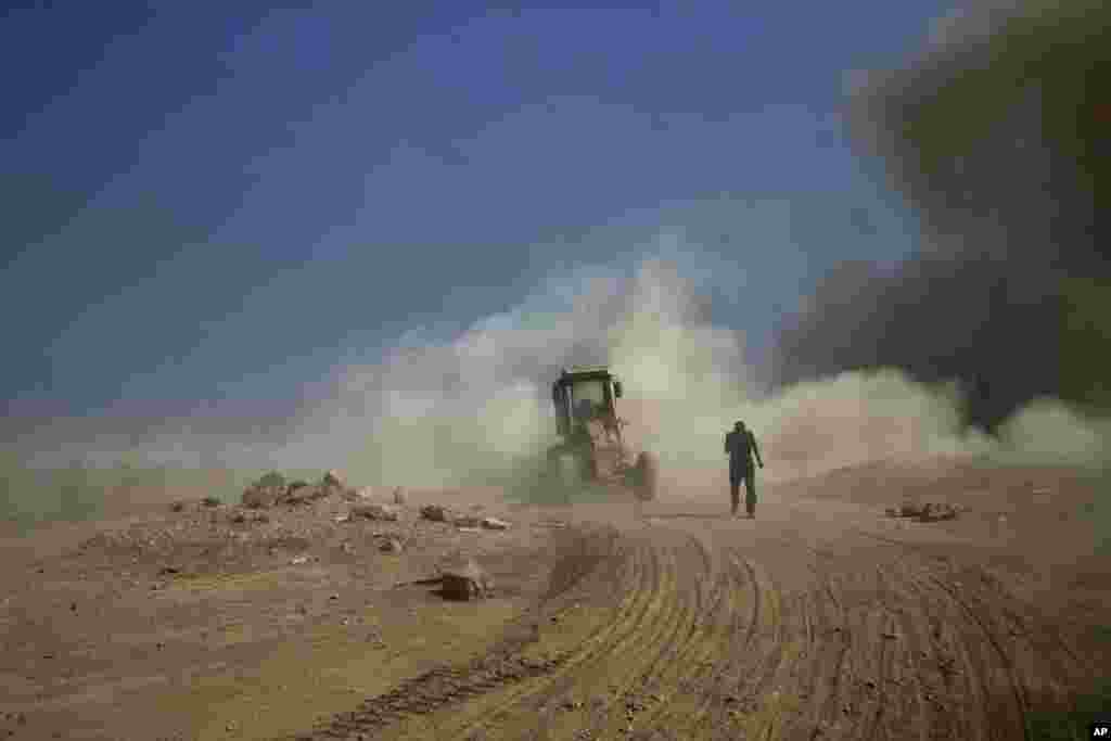 An Iraqi army contractor gets out of a road construction vehicle after being hit by an improvised explosive device on the outskirts of Qayyarah, Iraq.