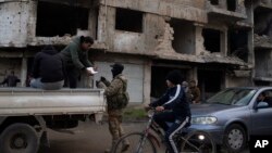 A member of the new armed forces, a former rebel who took part in the overthrow of Bashar Assad's government, checks the ID of a person at a checkpoint in the district of Khalidiya, Homs, Syria, Jan. 1, 2025.