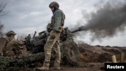 Ukrainian service members fire a howitzer M119 at a front line near Bakhmut