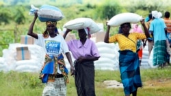 FILE: Women carry bags of maize during a food aid distribution excercise in Mudzi about 230 kilometres northeast of the capital Harare, Zimbabwe, Feb, 20, 2020.
