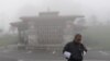 a Bhutanese man looks at his phone on a foggy day at Dochula Pass.