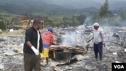 Warga mengamati puing-puing rumah yang terbakar dalam bentrok antar warga di Ilaga Papua awal bulan ini (1/8).